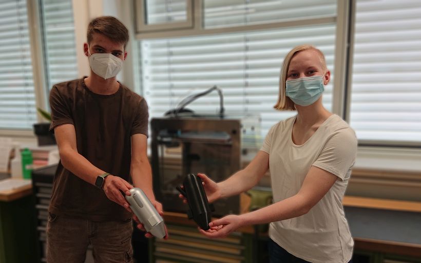 Ein Schüler und eine Schülerin halten den Prototyp eines Wasserfilters in den Händen.